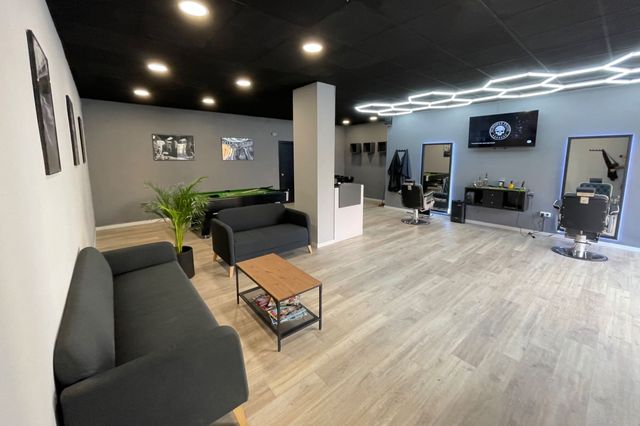 Interior de Vidal G Barber: sillones negros, luces hexagonales y suelo de madera